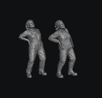 Two grey 3D-printed miniature figures of female farmers wearing work clothes and holding their aching backs.