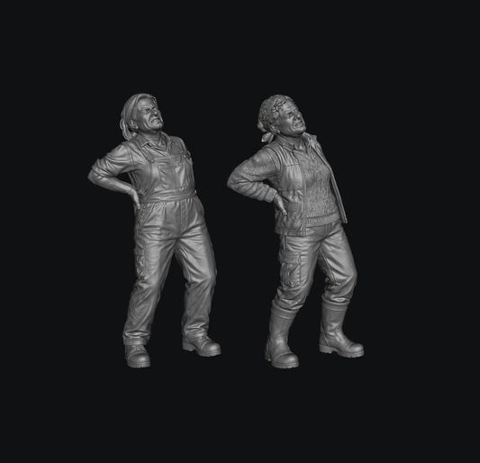 Two grey 3D-printed miniature figures of female farmers wearing work clothes and holding their aching backs.